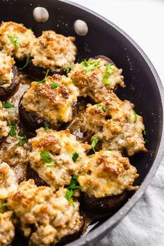 stuffed mushrooms with cheese and parsley in a skillet on a white tablecloth