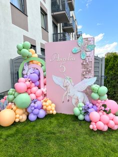 there is a sign with balloons on the grass in front of a building that says angelia