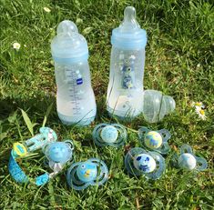 several baby bottles and pacifiers laying on the grass