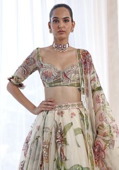 Featuring an ethereal ivory lehenga in a summer print and adorned with delicate embroidery. Paired perfectly with a matching classic blouse with a ruffle detail and a printed dupatta with glam sequins. This floral lehenga radiates elegance and grace and is ideal for a Sangeet or Mehendi at a destination party ! Composition : Lehenga, Blouse, Dupatta - Organza Care: Dry Clean Only and Vacuum Storage This product can be customized for sleeves, length of blouse and neckline Delivery : 4-6 weeks as the product is hand crafted. Check Size Guide or choose MySize for free customisation (All Sizes above XL can be made at 15% additional cost) For more information and sizes please contact fabiliciousfashion@gmail.com or visit our Copenhagen studio. About the Designer : Mahima Mahajan is best known f Elegant Organza Lehenga For Summer, Elegant Semi-stitched Floral Print Choli, Elegant Summer Organza Lehenga, Elegant Floral Print Georgette Sharara, Elegant Floral Print Lehenga For Festive Occasions, Summer Reception Lehenga With Sheer Dupatta, Elegant Floral Print Choli For Festive Occasions, Elegant Festive Floral Print Choli, Fitted Organza Lehenga With Floral Print