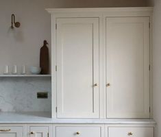 a white kitchen with marble counter tops and cabinets in the backround, next to a wine glass rack