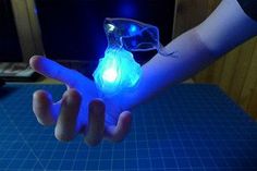 a person holding an object in their hand with blue light on it's fingers