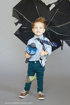 a young boy is holding an umbrella and speaking into a microphone while standing in front of a gray background