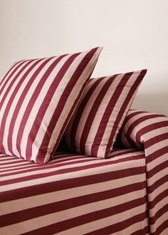 two red and white striped pillows sitting on top of a bed next to each other