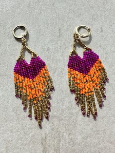 two pairs of beaded earrings with orange, purple and yellow beads hanging from hooks