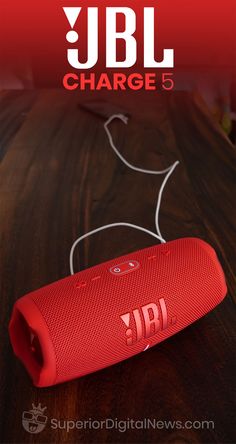 the jbl charge 5 portable speaker is shown on a wooden table with red lettering