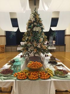 a table topped with lots of fruit and a christmas tree on top of the table