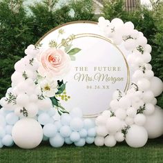 a sign with balloons and flowers on it in the middle of grass next to bushes