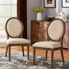 two gray chairs sitting on top of a rug in front of a wooden dresser and window