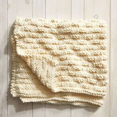 a crocheted dishcloth on a white wooden surface with wood grained boards in the background