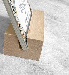 an open book sitting on top of a wooden block in the middle of concrete flooring