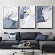 three paintings hang on the wall above a couch in a living room with a coffee table