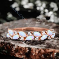 an opal and diamond ring sitting on top of a rock