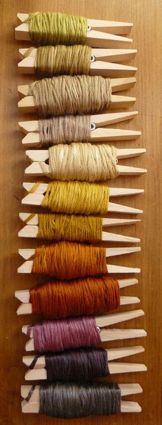 several skeins of yarn are arranged in rows on a wooden surface, each with different colors