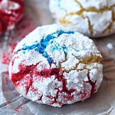 two red, white and blue cookies are sitting on wax paper with sprinkles