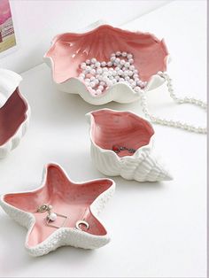 three star shaped dishes with pearls in them on a table next to a white wall