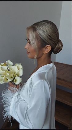 a woman with blonde hair holding flowers in her hand