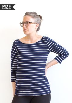 a woman standing in front of a white wall with her hands on her hips wearing glasses