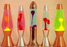 four different colored vases sitting next to each other on a counter top in front of a wall