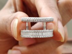 a woman's hand holding an open ring with three rows of diamonds on it