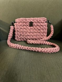 a pink crocheted purse sitting on top of a green couch