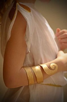 a woman wearing gold bracelets and a white shirt