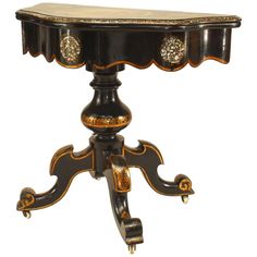 an ornate black and gold table with two drawers on it's legs, sitting against a white background