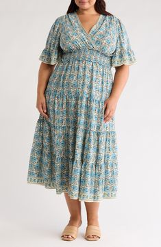 Covered in a fun and colorful print, this surplice V-neck dress features a smocked waist and tiered skirt for a graceful look. Surplice V-neck Short sleeves 53 1/2" length (size 2X) 100% polyester Machine wash, line dry Imported Model stats: 5'10" height, 41" bust, 36" waist, 48" hip. Model is wearing size 2X. Flowy Bohemian V-neck Tiered Dress, Flowy Bohemian Tiered V-neck Dress, Flowy V-neck Smocked Dress, Blue Floral Print Tiered Dress, Tiered Beach Dress With Elastic Waistband, Bohemian V-neck Midi Dress With Smocked Bodice, Flowy Bohemian Smocked V-neck Dress, Bohemian Tiered Dress With Smocked Back, Summer V-neck Smocked Dress With Elastic Waistband