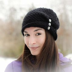 a woman with long hair wearing a black knitted hat and smiling at the camera