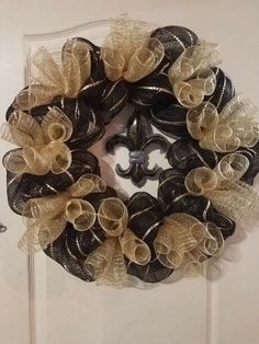 a black and gold wreath hanging on the front door with a fleur de lys