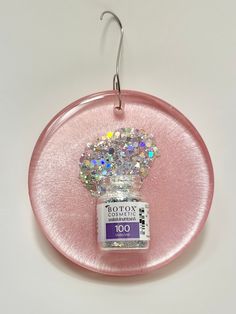 a pink plate with a small crystal crown on it's side and a hook in the middle