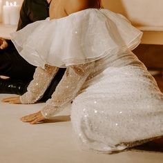 a woman in a white dress is sitting on the floor with her legs spread out