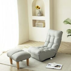 a living room with a chair and ottoman on the floor next to a potted plant