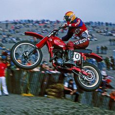 a person on a dirt bike doing a trick in the air with people watching behind him