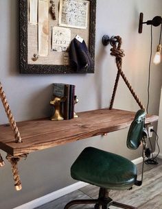 a wooden desk with rope hanging from it's sides and a green chair next to it