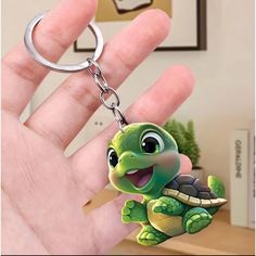 a hand holding a keychain with a small turtle on it