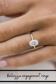 a woman's hand with a diamond ring on her left hand and the other hand holding an engagement ring