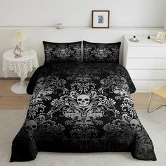 a black and white bed with skulls on the cover is in a room next to a chair