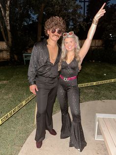 a man and woman dressed in costumes posing for a photo with police tape behind them