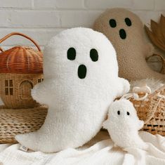 two stuffed ghost toys sitting on top of a bed