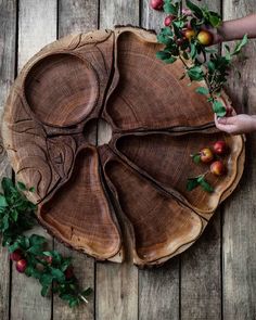 a wooden tray with apples on top of it next to some leaves and berries hanging from the tree