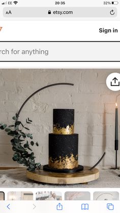 a black and gold cake sitting on top of a wooden stand next to a white brick wall