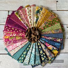 an assortment of colorful fabrics arranged in a circle on top of a wooden table with white boards