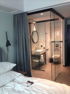 a bathroom with a glass shower stall next to a bed