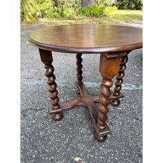 a wooden table sitting on top of a cement ground next to trees and bushes in the background