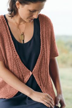 a woman sitting down wearing a brown cardigan