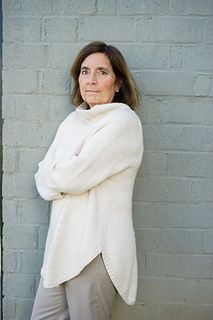 a woman leaning against a wall with her arms crossed