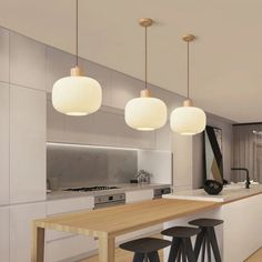 three lights hanging from the ceiling above a kitchen island with stools and countertop