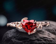 a red heart shaped ring sitting on top of a rock