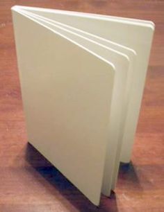 three white folders are stacked on top of each other in front of a wooden floor